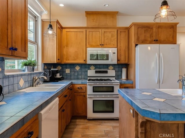 kitchen featuring tile countertops, sink, white appliances, and hanging light fixtures