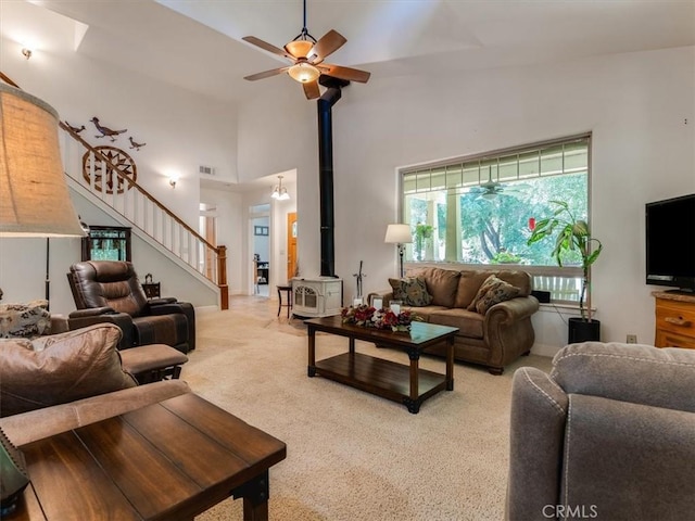 living room featuring carpet, ceiling fan, a wood stove, and a towering ceiling