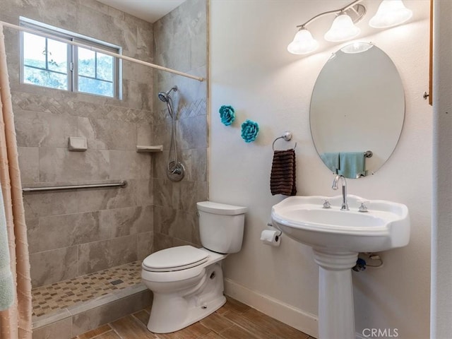 bathroom with a tile shower and toilet