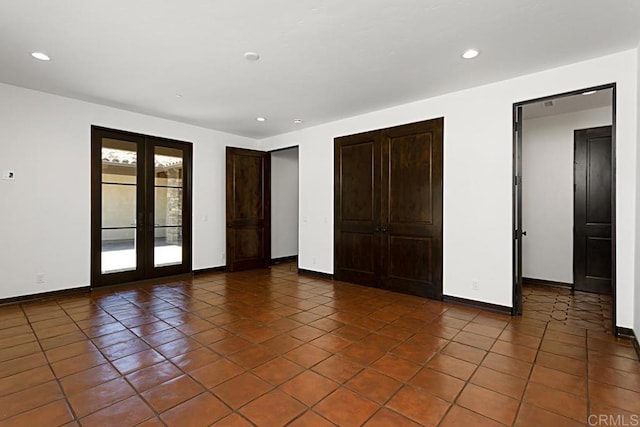 unfurnished bedroom with dark tile patterned flooring, access to outside, and french doors