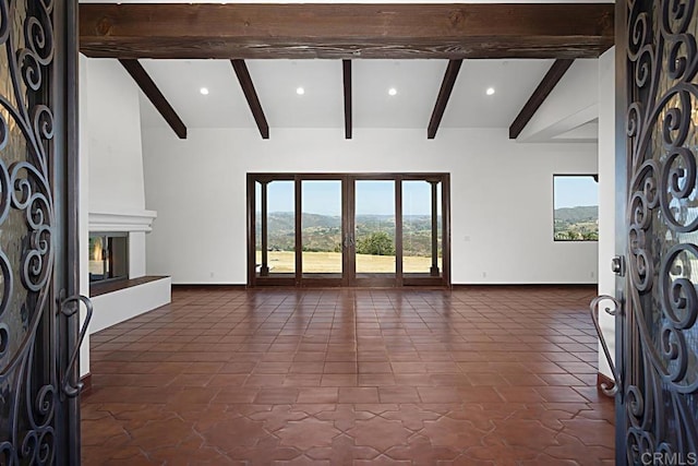 unfurnished living room featuring baseboards, a large fireplace, and beam ceiling