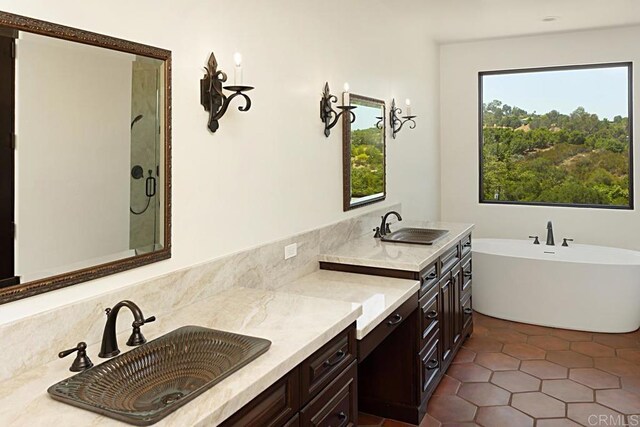 bathroom with tile patterned floors, a sink, a stall shower, and a soaking tub