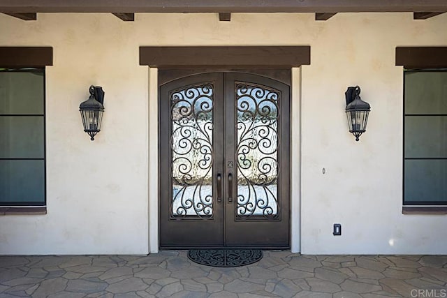 view of exterior entry featuring french doors and stucco siding