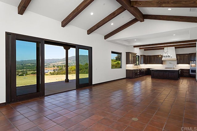 unfurnished living room featuring dark tile patterned floors, a sink, a mountain view, recessed lighting, and vaulted ceiling with beams