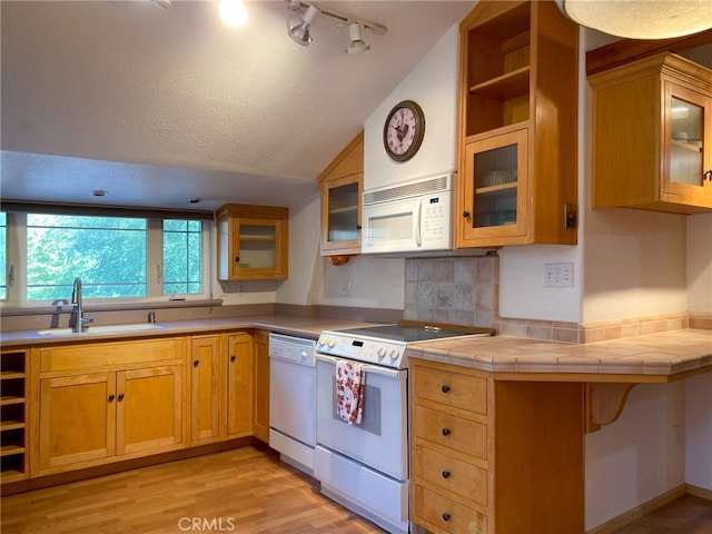 kitchen featuring white appliances, sink, light hardwood / wood-style floors, a textured ceiling, and lofted ceiling