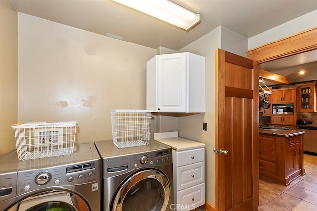 washroom featuring cabinets, washer and clothes dryer, and light tile floors