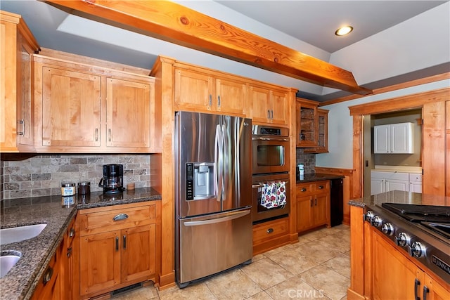 kitchen with dark stone countertops, stainless steel appliances, backsplash, and light tile floors