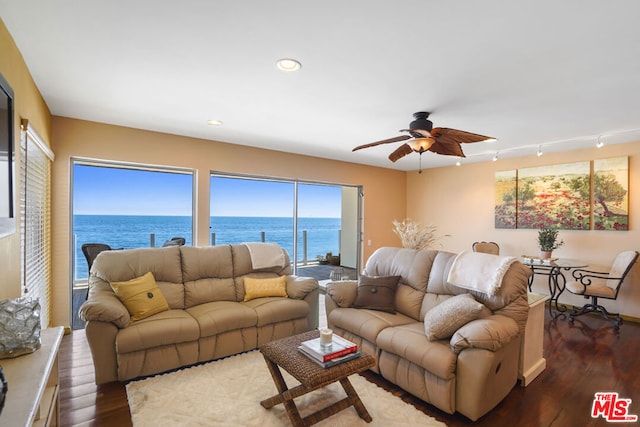 living room with a water view, ceiling fan, track lighting, and dark wood-type flooring