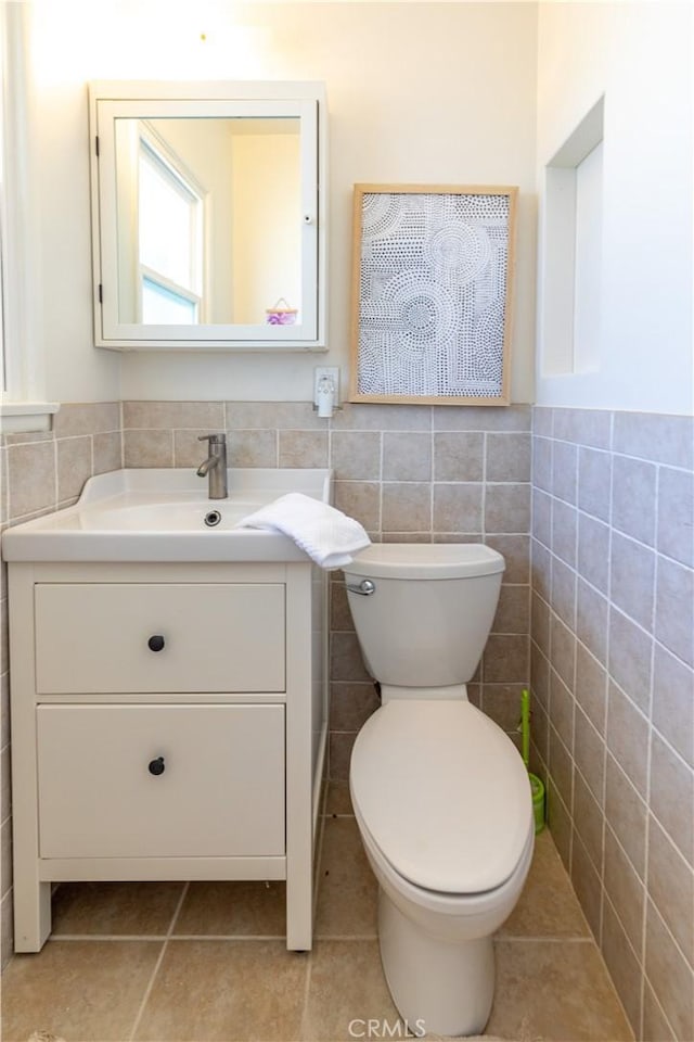 bathroom with tile patterned floors, vanity, toilet, and tile walls