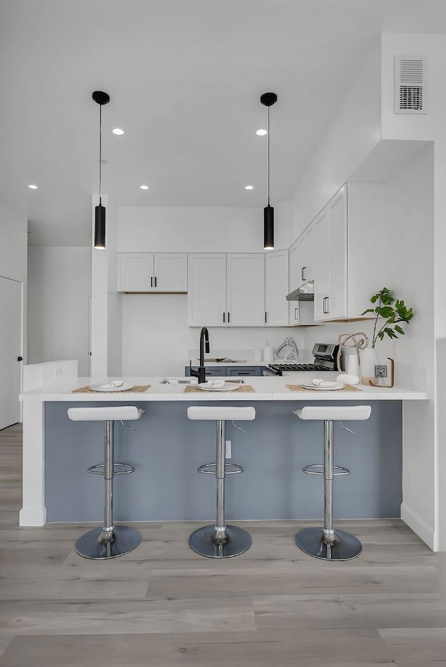 kitchen featuring a kitchen bar, white cabinets, kitchen peninsula, and gas stove