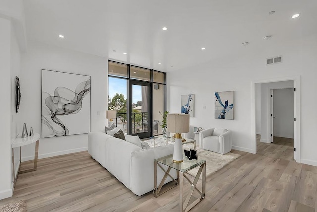 living room featuring a wall of windows and light hardwood / wood-style floors