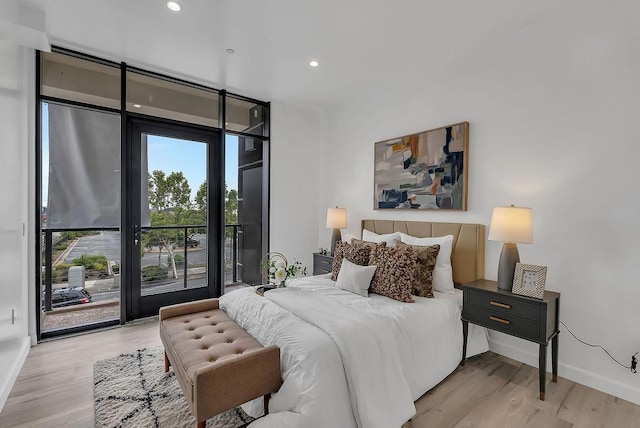 bedroom with a wall of windows, access to outside, and light wood-type flooring