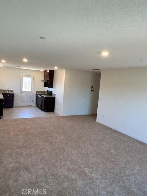 unfurnished living room with light carpet and a textured ceiling