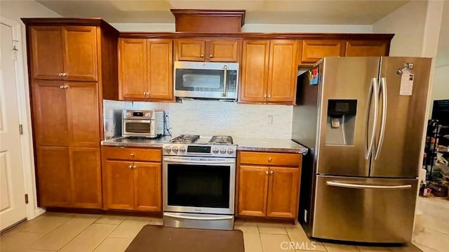 kitchen featuring appliances with stainless steel finishes, tasteful backsplash, and light tile patterned floors