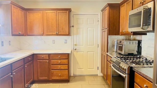 kitchen featuring tasteful backsplash, light tile patterned floors, and stainless steel appliances