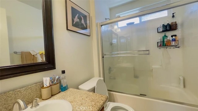 full bathroom featuring vanity, combined bath / shower with glass door, and toilet