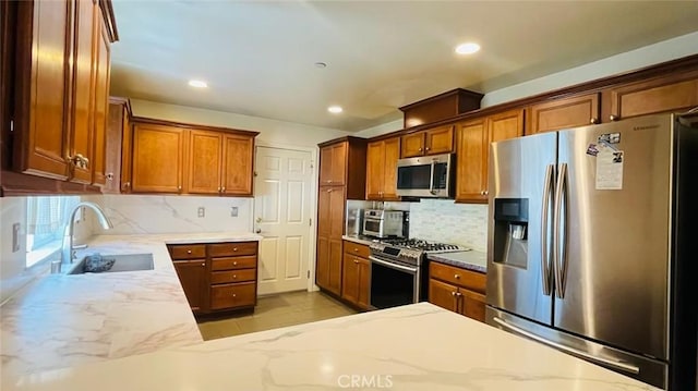 kitchen featuring light stone countertops, sink, appliances with stainless steel finishes, and tasteful backsplash