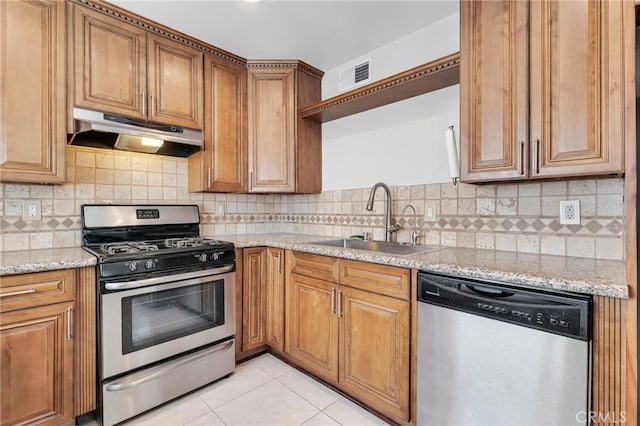 kitchen with backsplash, sink, light stone countertops, and stainless steel appliances