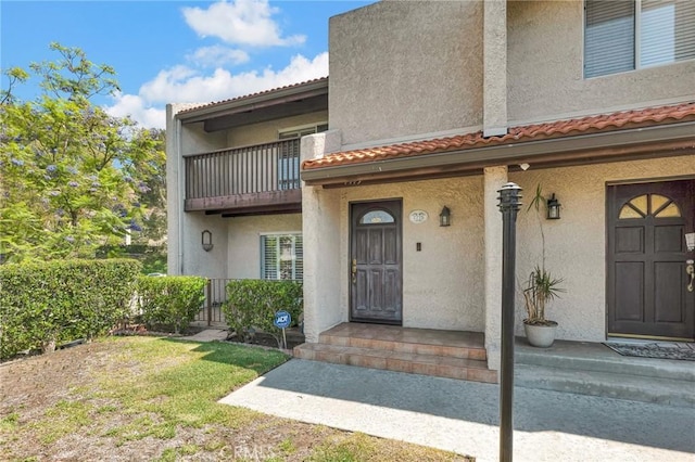 view of exterior entry featuring a balcony and a yard