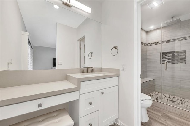 bathroom featuring walk in shower, vanity, wood-type flooring, and toilet