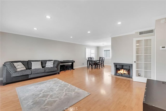 living room with crown molding and light hardwood / wood-style flooring