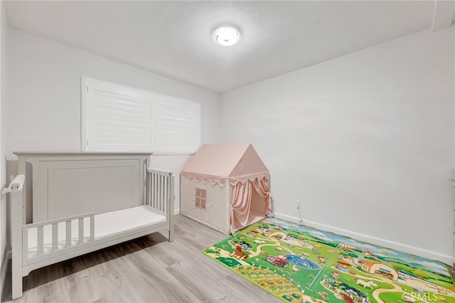 unfurnished bedroom with light hardwood / wood-style floors and a crib