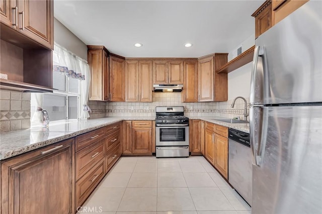 kitchen with light stone countertops, sink, backsplash, light tile patterned flooring, and appliances with stainless steel finishes