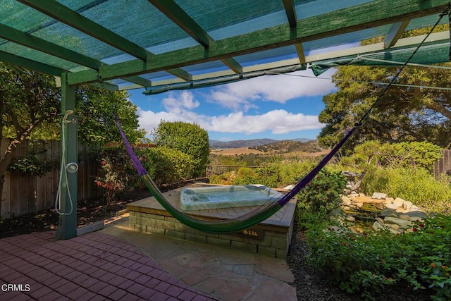 view of patio / terrace with a mountain view, fence, a pergola, and an outdoor hot tub