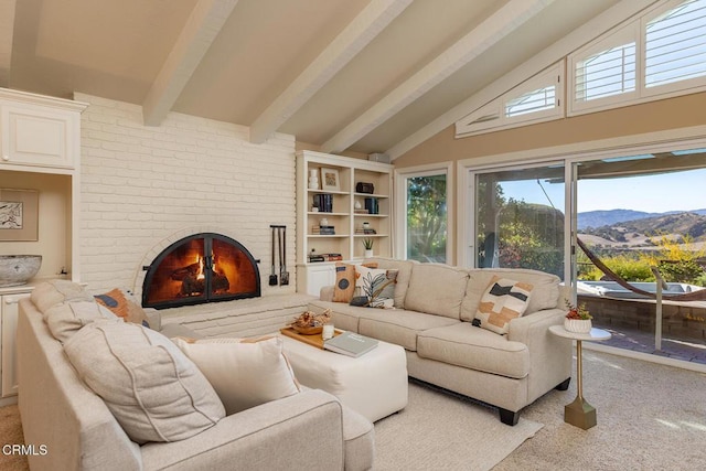 living area featuring beamed ceiling, a healthy amount of sunlight, a mountain view, and carpet