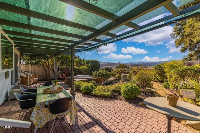 view of patio / terrace featuring a mountain view, fence, outdoor dining space, and a pergola