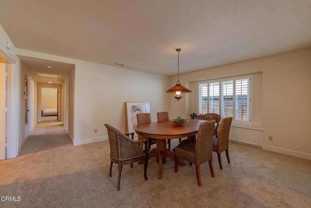 dining room with baseboards, visible vents, and light carpet