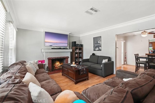 living room featuring a fireplace, light hardwood / wood-style floors, ceiling fan, and ornamental molding