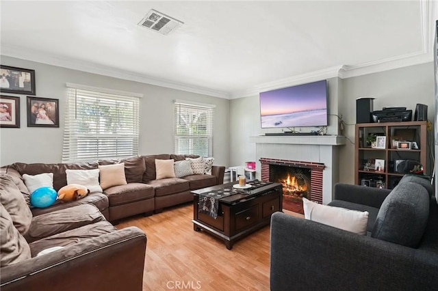 living room featuring light hardwood / wood-style floors, crown molding, and a brick fireplace