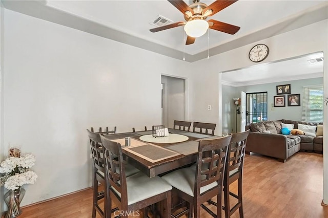 dining room with ceiling fan, light hardwood / wood-style floors, and a raised ceiling