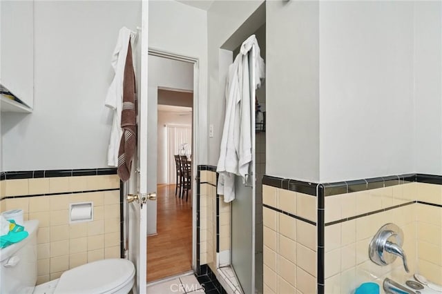 bathroom with tile patterned flooring, toilet, tile walls, and walk in shower