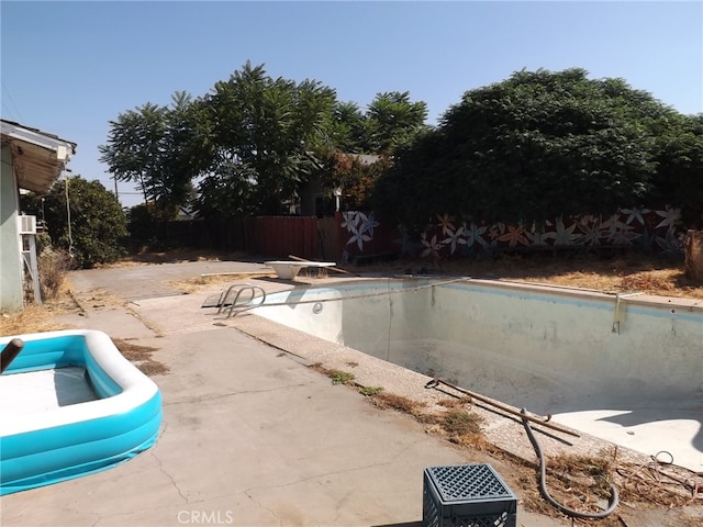 view of swimming pool featuring a diving board and a patio