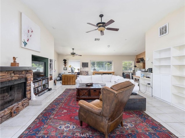 living room with ceiling fan, a fireplace, light tile patterned floors, and lofted ceiling