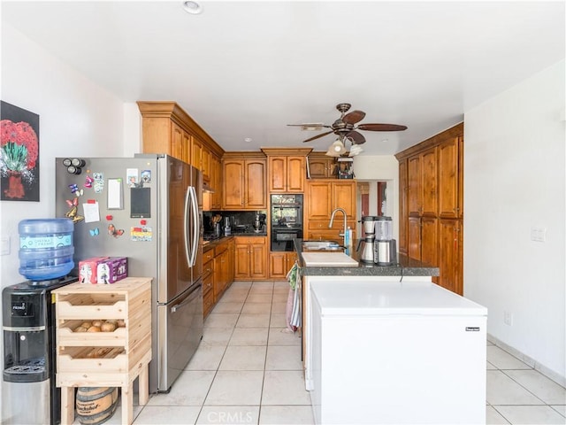 kitchen with a kitchen island with sink, ceiling fan, light tile patterned flooring, and fridge