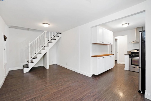 interior space featuring wood counters, stainless steel stove, white cabinets, dark hardwood / wood-style floors, and fume extractor