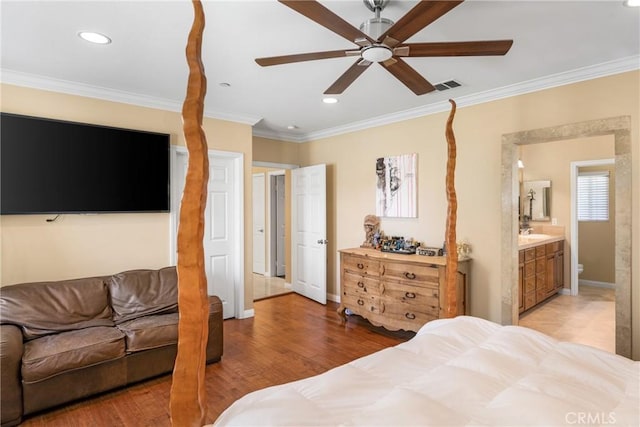 bedroom featuring connected bathroom, light hardwood / wood-style flooring, ceiling fan, and crown molding