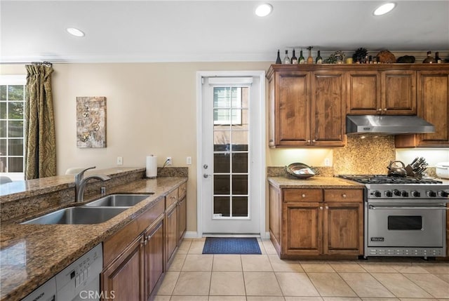 kitchen with sink, tasteful backsplash, dark stone counters, designer range, and light tile patterned flooring