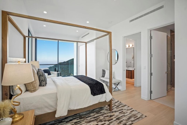 bedroom featuring light wood-type flooring and ensuite bath