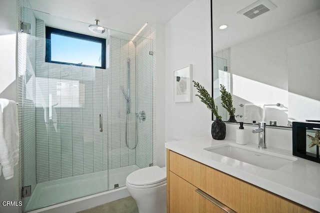 bathroom featuring vanity, a shower with shower door, and toilet