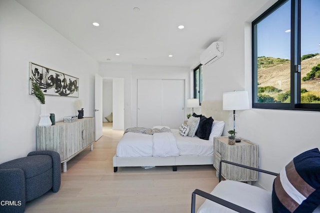 bedroom with light hardwood / wood-style floors and a wall mounted AC