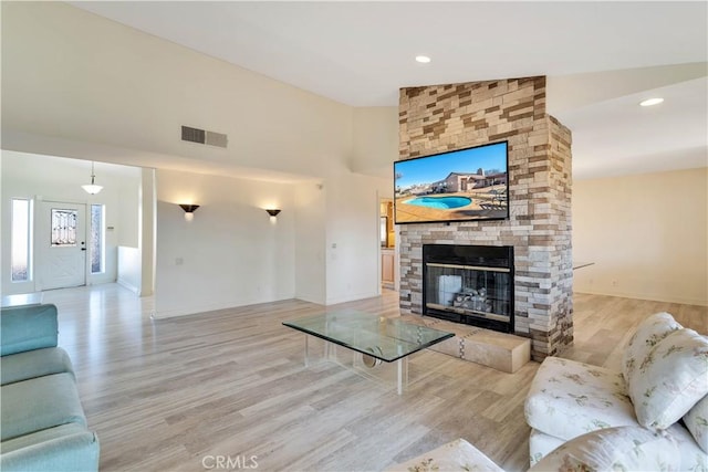 living room featuring lofted ceiling, a fireplace, and light hardwood / wood-style flooring