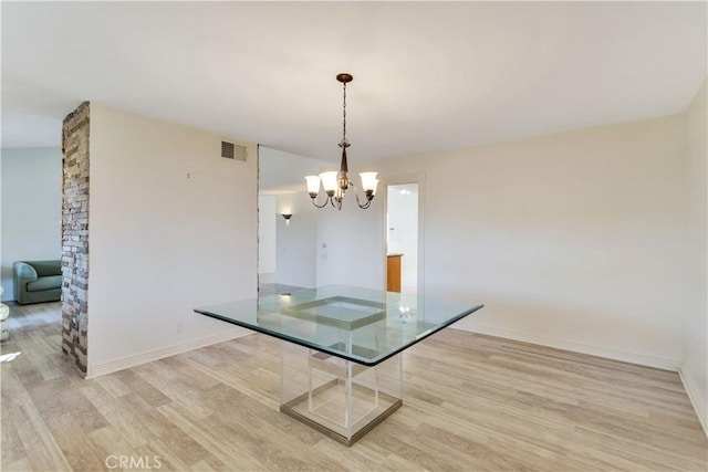 unfurnished dining area featuring light wood-type flooring and an inviting chandelier