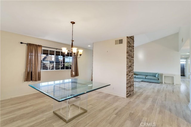 unfurnished dining area with lofted ceiling, light wood-type flooring, and a chandelier