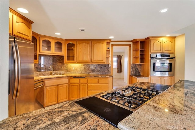 kitchen with light stone countertops, sink, and appliances with stainless steel finishes