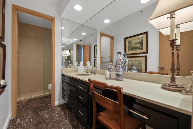 bathroom with toilet, vanity, and tiled shower