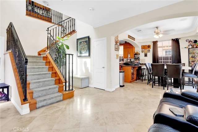 tiled living room featuring ornamental molding, ceiling fan, and a tray ceiling